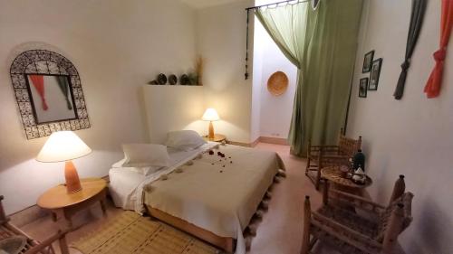 Schlafzimmer mit einem Bett, einem Tisch und einem Fenster in der Unterkunft Dar El Kharaz in Marrakesch