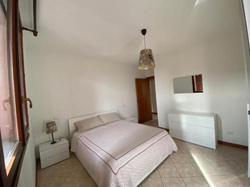 Dormitorio blanco con cama y lámpara colgante en Appartamento la Pioppa con posto auto e Wi-Fi en Castelfranco Emilia
