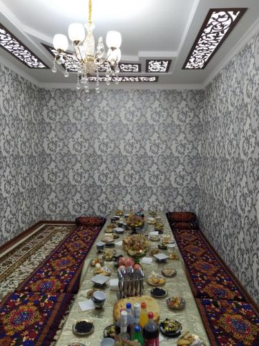une longue table avec des assiettes de nourriture dans une pièce dans l'établissement Khiva Otabek Hotel, à Khiva