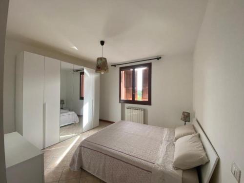 Habitación blanca con cama y ventana en Appartamento la Pioppa con posto auto e Wi-Fi en Castelfranco Emilia