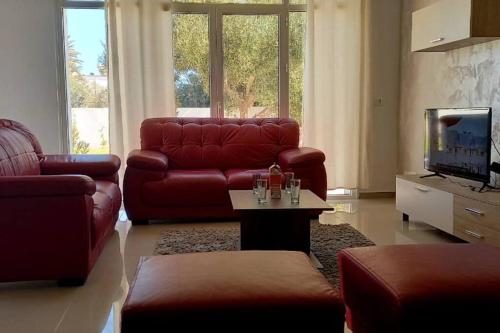 a living room with a red leather couch and a tv at Magnifique villa avec piscine sur l’île de Djerba pour vacances in Arkou