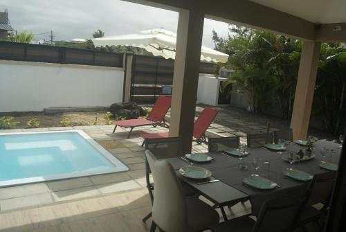 a dining table and chairs on a patio with a pool at Villa Le Mahé in Beau Vallon