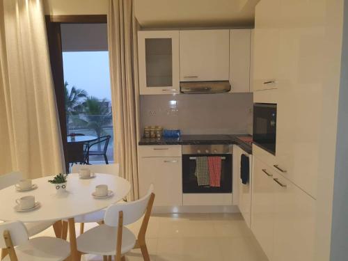 a white kitchen with a table and a table and chairs at Acacia Flower AC 8-201 in Salalah