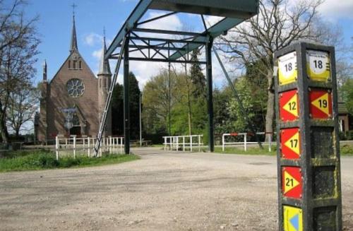 a sign in front of a church with a clock tower at Logement In de Peel in Griendtsveen