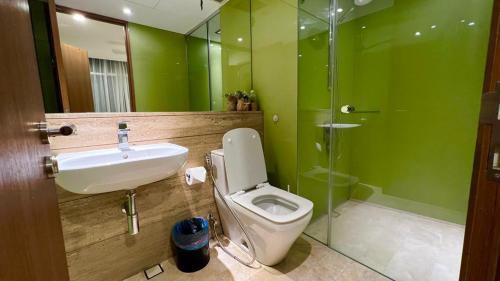 a green bathroom with a toilet and a sink at Soho suite apartment hotel in Kuala Lumpur