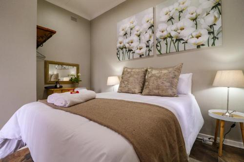 1 dormitorio con 1 cama con flores blancas en la pared en The Honeycomb 2, en Kimberley