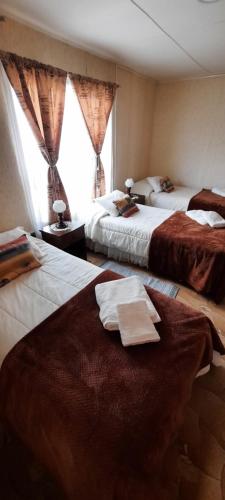 a hotel room with two beds with towels on them at Hostal Los Pinos in Puerto Natales