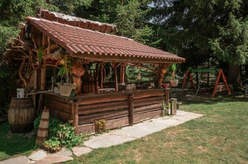 a wooden gazebo with a roof in a yard at Lusi Holiday, Смолянски езера in Smolyan