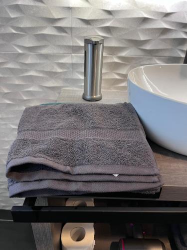 a stack of towels on a table next to a sink at Minardi Apartments in Vercelli