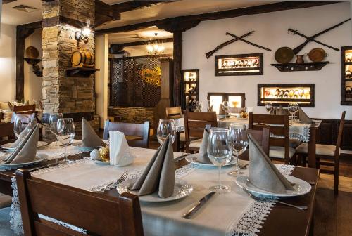 a dining room with a table with napkins and wine glasses at Lusi Holiday, Смолянски езера in Smolyan