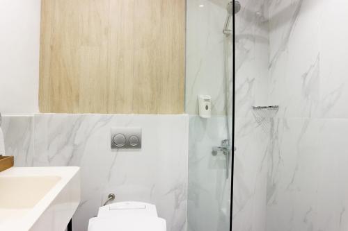 a bathroom with a shower and a toilet and a sink at Cordia Hotel Banjarmasin - Hotel Dalam Bandara in Pulaubiruang