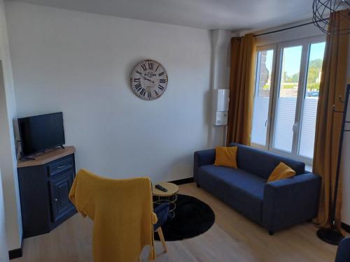- un salon avec un canapé bleu et une horloge murale dans l'établissement Nid douillet ernee, à Ernée