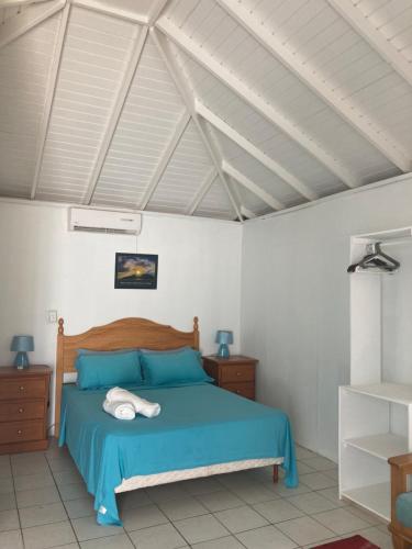 a bedroom with a blue bed and white walls at The Lodge - Antigua in English Harbour Town