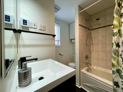 a white bathroom with a sink and a shower at Le Repère du Mont-Saint-Anne in Beaupré