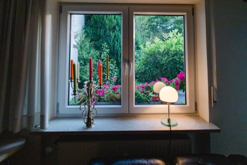 a window with a view of a garden with flowers at Modernes und gemütliches Designerzimmer in Langensteinbach