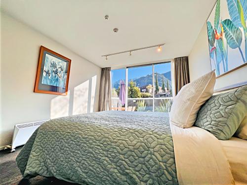 クイーンズタウンにあるTravellers Delight Queenstown Hillのベッドと大きな窓のある寝室