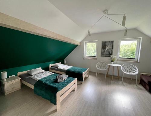 a bedroom with two beds and a green wall at Cicha Ostoja in Miłków