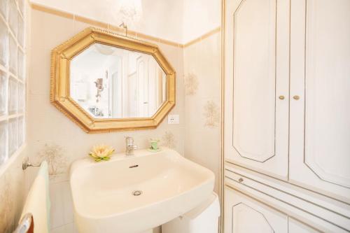 uma casa de banho branca com um lavatório e um espelho em Dimora Bellavista,garage privato,due piani em Sanremo