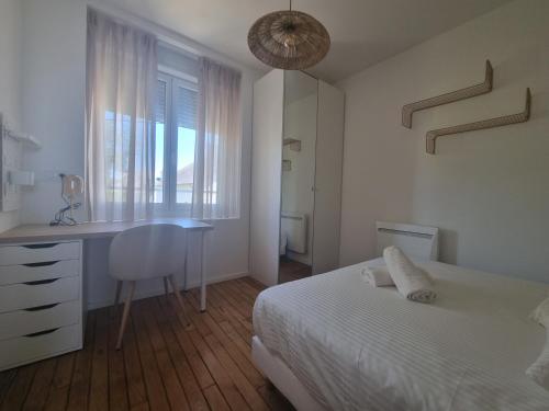 1 dormitorio con cama, escritorio y ventana en Le Reflet Papillon by Madame Conciergerie en Bruz