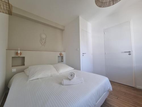 ein weißes Schlafzimmer mit einem weißen Bett und einem Handtuch darauf in der Unterkunft Le Reflet Papillon by Madame Conciergerie in Bruz