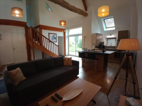 een woonkamer met een zwarte bank en een keuken bij DOMAINE DES TISSEYS vue sur le Mont St Michel in Dragey