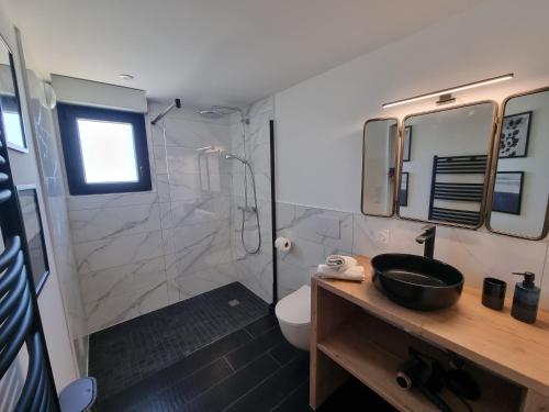 een badkamer met een douche, een wastafel en een toilet bij L'Or Noir by Madame Conciergerie in Bruz
