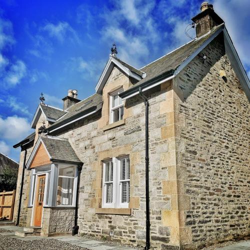 an old brick building with white windows and a roof at Laburnam Villa - Luxury 4 bedroom accommodation in the heart of Killin in Killin