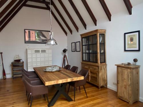 a dining room with a wooden table and chairs at Das Atelier in Krummhörn