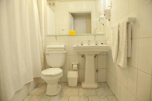 a white bathroom with a toilet and a sink at Hotel Santa Lucia in Santiago