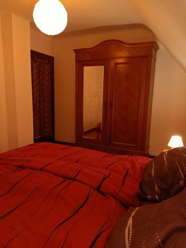 a bedroom with a red bed and a wooden cabinet at Room Algo in Algolsheim