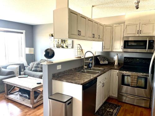 a kitchen with white cabinets and a counter top at Top Floor Riverfront Condo with Stellar Sunsets! in Fort McMurray