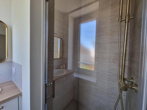 uma casa de banho com um chuveiro e um lavatório. em Le Coco Doré by Madame Conciergerie em Bruz
