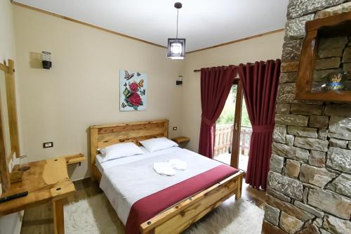 1 dormitorio con cama y pared de piedra en Bujtina SHKODRANI, en Voskopojë