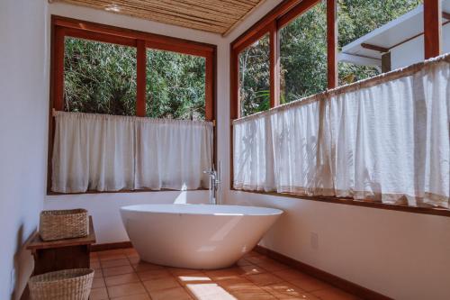 a bathroom with a large tub in front of windows at Fazenda Santa Vitória in Queluz