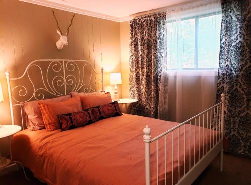 - une chambre avec un lit doté de draps orange et une fenêtre dans l'établissement 1400sf self checkin modern chalet AC Grill Firepit, à Thornhurst