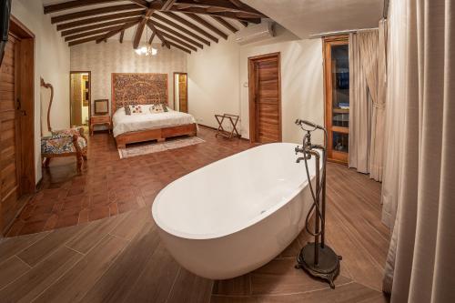 a large bathroom with a bath tub and a bedroom at PETRA SANTA HOTEL BOUTIQUE in Pereira