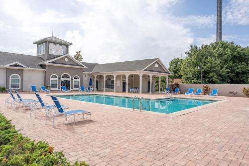 a swimming pool with blue chairs and a house at 10 Min to Disney,Renovated 3BR Condo,Sleeps,Resort Pool in Kissimmee