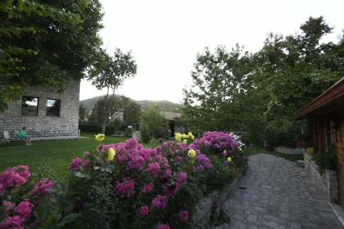 a garden with purple and yellow flowers next to a house at Bujtina SHKODRANI in Voskopojë