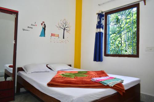 a bedroom with a bed with a window and a blanket at Jaldapara Binaychapa homestay in Mādāri Hāt