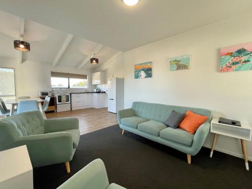 a living room with two blue couches and a kitchen at Pacific Park Christian Holiday Camp in Papamoa