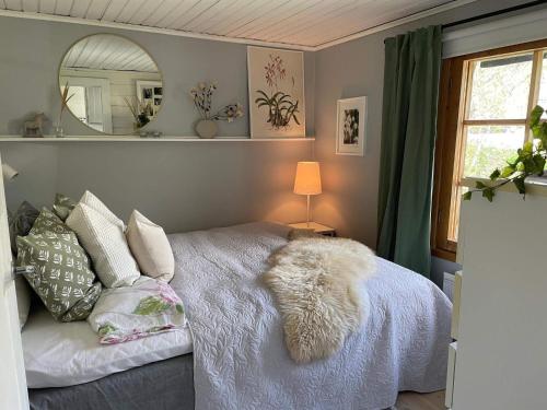 een slaapkamer met een wit bed met kussens en een spiegel bij Holiday home VäTö IV in Harg