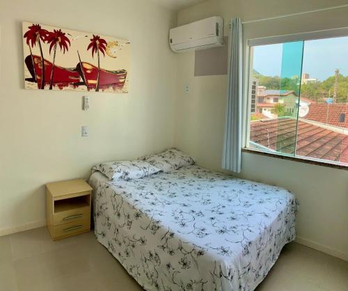 ein kleines Schlafzimmer mit einem Bett und einem Fenster in der Unterkunft Residencial Açores in Bombinhas