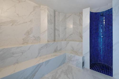 uma casa de banho com um chuveiro e azulejos azuis em Millenium Hotel Flat em Manaus