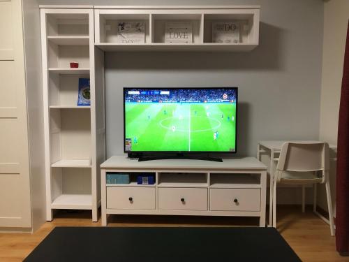a television on a white entertainment center with a soccer game at Your Home - Central studio apartment, balcony, parking & Self Check-in in Vilnius