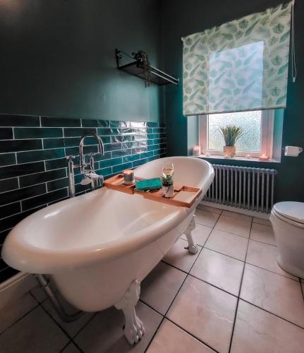a bathroom with a tub and a toilet and a window at Castleside House in Matlock