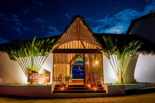 a building with a entrance with palm trees in front at Villa Zen Hotel in Camocim