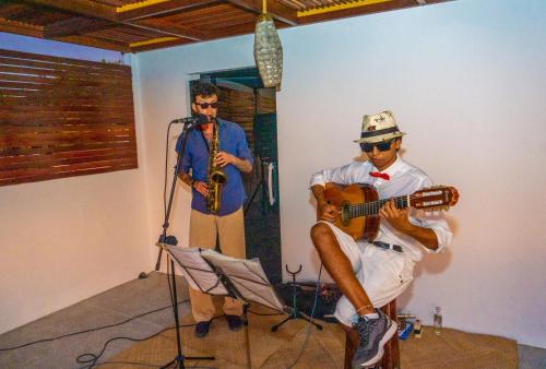 a man playing a guitar and a man playing a saxophone at Villa Zen Hotel in Camocim