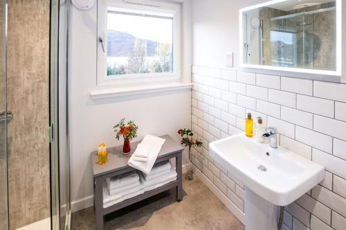a white bathroom with a sink and a window at Foinaven House in Ullapool
