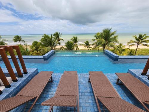 a view of a swimming pool with chairs and the beach at Loft com jacuzzi privativa frente mar do Bessa in João Pessoa