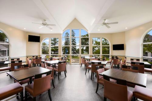 a dining room with tables and chairs and windows at Best Western Harbour Pointe Lakefront in Saint Ignace